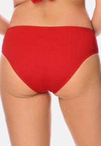 Parte inferiore di bikini rossa realizzata in tessuto liscio, con un design a vita alta e bordi puliti, che presenta un colore uniforme senza motivi.