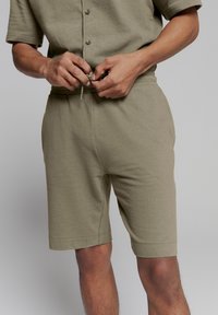 Olijfgroene shorts van zacht katoen met een elastische tailleband en trekkoord, voorzien van zijzakken en een ontspannen pasvorm.