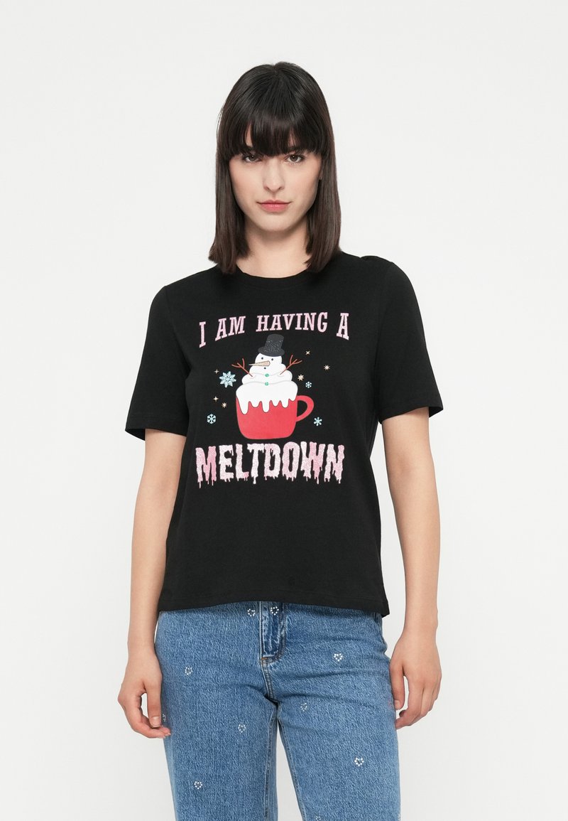 Žena s tmavými vlasmi, oblečená v čiernom tričku s nápisom "Prežívam meltdown" a grafikou roztápajúceho sa snehuliaka v červenom hrnčeku.