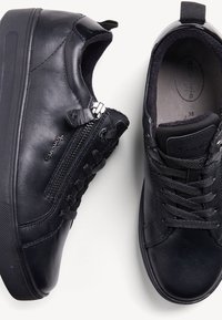 Baskets en cuir noir avec fermeture éclair, bout rond, côtés texturés et semelle en caoutchouc. Les lacets et une languette au talon renforcent la fonctionnalité.