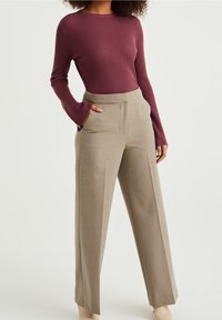 Ribbed maroon long-sleeve top paired with high-waisted, wide-leg beige trousers. Notable details include button accents at sleeve openings.