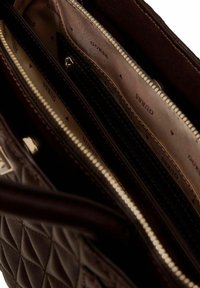 Sac à main matelassé marron avec accents dorés ; plusieurs compartiments avec une doublure beige de marque et des fermetures éclair. Texture en cuir lisse.