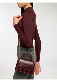 Bordowa torebka z sztucznej skóry z rączką u góry i złotym łańcuszkiem, charakteryzująca się eleganckim prostokątnym kształtem i gładką teksturą.