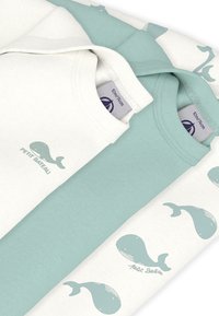 Τρία βαμβακερά T-shirts: ένα εκρού με σχέδιο φάλαινας και δύο τιρκουάζ με μοτίβα φάλαινας. Όλα διαθέτουν απαλό ύφασμα και στρογγυλές λαιμόκοψης.