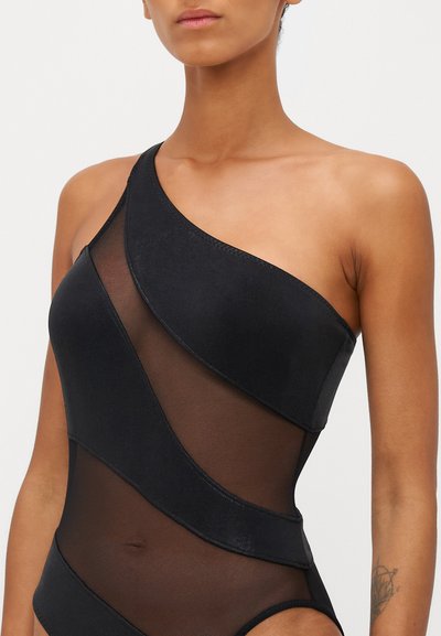 Schwarzer Ein-Schulter-Badeanzug mit kontrastierenden, transparenter Mesh-Einsätzen und glattem Material. Figurbetontes Design mit geschwungenen Nahtdetails.