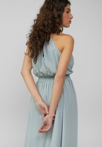 Himmelblaues, ärmelloses Kleid mit gerafftem Oberteil und elastischem Bund. Weicher, fließender Stoff mit glatter Textur und subtiler Glanz.