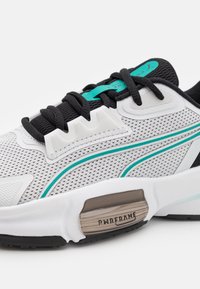 Sneaker featuring a white mesh upper, black accents, and teal details. Textured overlays and a PWRFRAME heel provide structure and support.
