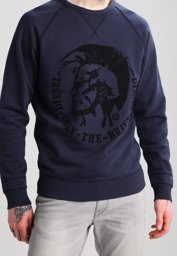 Felpa blu navy con colletto rotondo e maniche raglan. Presenta una grande grafica nera di un volto stilizzato e il testo "DIESEL ONLY-THE-BRAVE."