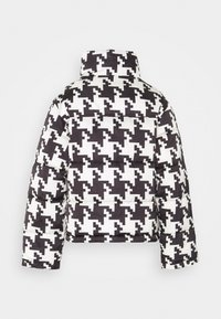 Puffjacka med ett svart och vitt hundtandsmönster, hög krage och vadderad textur med tryckknappar på ärmarna.