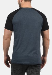 Men's t-shirt featuring a dark blue body with black raglan sleeves, made from soft fabric with a smooth texture and a casual fit.