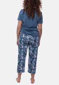 Blauwe katoenen t-shirt gecombineerd met cropped broeken met een bloemenpatroon in tinten van blauw, wit en zwart. Casual pasvorm; geen zichtbare hardware.