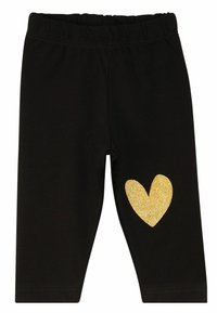 Sorte leggings med et blødt, strækbart stof og en elastisk talje, prydet med et stort glitrende guldhjerte på venstre ben.