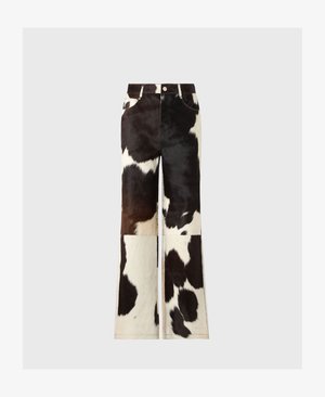 Pantalones acampanados de piel de vaca con un diseño de patchwork en colores blanco y negro, con una textura suave y costuras visibles.