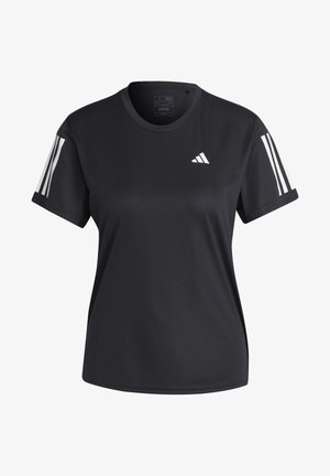 Osoba ubrana w czarną sportową koszulkę i szorty z białymi sneakersami, stoi z rozłożonymi ramionami i lekko rozsuniętymi nogami na białym tle.
