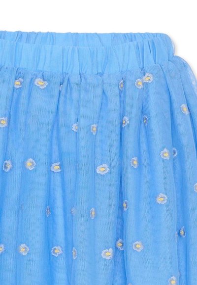 Blauwe tule rok met een elastische tailleband, versierd met geborduurde witte madeliefjes met gele centra die gelijkmatig over de stof zijn verdeeld.