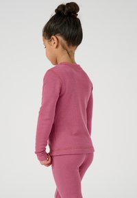 Maglietta rosa a maniche lunghe e leggings coordinati per bambini, realizzati in cotone tessurizzato. Presenta un colletto rotondo e maniche aderenti.