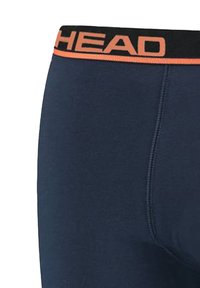 Marineblaue Herrenunterwäsche mit einem schwarz-orangen elastischen Bund, auf dem das Wort "HEAD" steht. Glattes Material mit flachen Nähten.