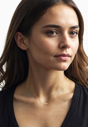 Collana d'oro con un piccolo pendente a croce, caratterizzata da delicate maglie e piccoli dettagli a perla. Indossata da un modello con abbigliamento scuro e capelli lisci.