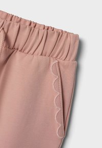 Svijetlo ružičaste hlače s elastičnim strukom i detaljem s rebrastim ivicama sa strane, izrađene od mekog, rastezljivog materijala.