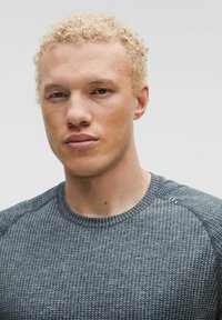 Koszulka sportowa w ciemnoszarym kolorze z teksturowanym wzorem. Posiada okrągły dekolt i krótkie rękawy. Gładki materiał o dopasowanym kroju.