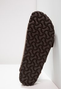 Suela de zapato de goma marrón con un diseño texturizado en patrón de olas, que presenta empuñaduras contorneadas para tracción y estabilidad.