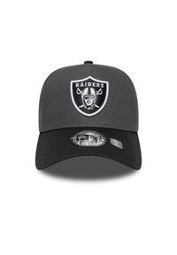 Szürke baseball sapka fekete napellenzővel, az elején hímzett Raiders logóval. Állítható zárás és New Era branding látható.