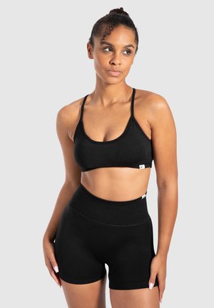 Zwart sportset bestaande uit een cropped tanktop met dunne bandjes en high-waisted shorts, gemaakt van een gladde, elastische stof.