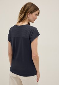 Haut bleu marine à manches courtes avec un design rayé texturé au dos, coupe décontractée et ourlet arrondi. Tissu léger.