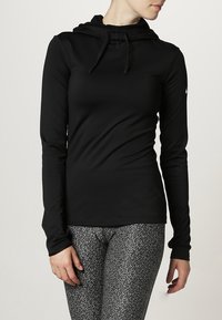 Sudadera negra de manga larga hecha de una tela suave y elástica con capucha ajustable. Combinada con leggings estampados que presentan un diseño en gris y negro.