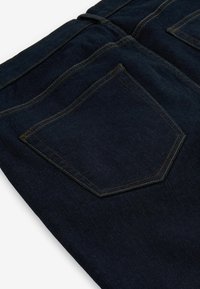 Dunkelblaue Jeans mit einem markanten Taschendesign und goldenen Nähten, glatter Textur und geradem Beinverlauf für eine maßgeschneiderte Passform.