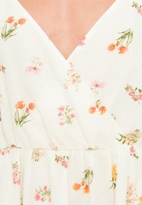 Λευκό φόρεμα με φλοράλ μοτίβο, με ντεκολτέ σε σχήμα V, διακοσμημένο με μικρά ροζ και πορτοκαλί λουλούδια, κατασκευασμένο από ελαφρύ, υφασμάτινο ύφασμα με υφή και με ζώνη στη μέση που συλλέγεται.