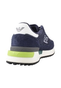 Sneaker blu navy con un upper in suede texture, dettagli bianchi, una striscia verde nella parte intermedia della suola e un logo prominente sul tallone.