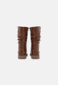 Bottes hautes en cuir marron avec un design décontracté, fermeture éclair et semelle marron texturée. Surface lisse avec des détails de couture subtils.