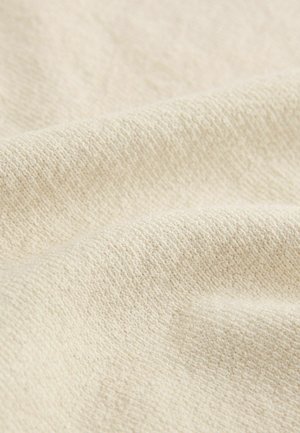 Tela de color beige claro con un patrón texturizado y tejido. La superficie parece suave y ligeramente estriada, mostrando hilos finos y uniformes.