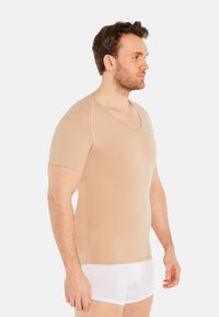 Beige short-sleeve shirt with a V-neck design, made of smooth, stretchy fabric, fitted to the body, with subtle stitching details.