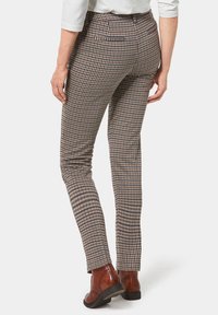 Geruite broeken in bruin en crème met een slim fit, voorzien van achterzakdetails en gedragen met bruine schoenen. Gelaagd stof.