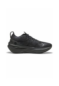 Black athletic shoe with a textured mesh upper, curved sole, and distinctive cushioning. Features lace-up closure and branding on the side.