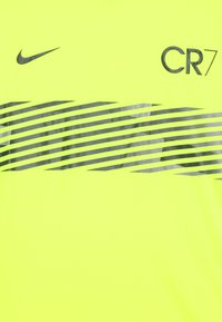 Neon żółta koszulka sportowa Nike z poziomymi czarnymi paskami i szarym logo "CR7". Gładka faktura o właściwościach odprowadzających wilgoć.