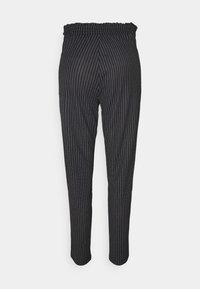 Svart ränder byxor med elastisk midja, avsmalnande ben och en slät textur. Ränderna har tunna vita linjer på en mörk bakgrund.