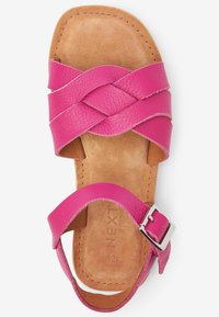 Sandal in pelle rosa con un design a tracolla intrecciata, una suola piana in camoscio color nocciola e una fibbia in argento sulla cinghia della caviglia.
