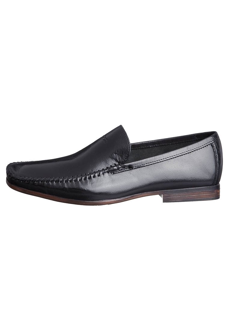 Mocassins en cuir noir avec un design cousu sur le devant, une finition lisse, un talon bas et un bout arrondi, offrant une apparence classique et élégante.