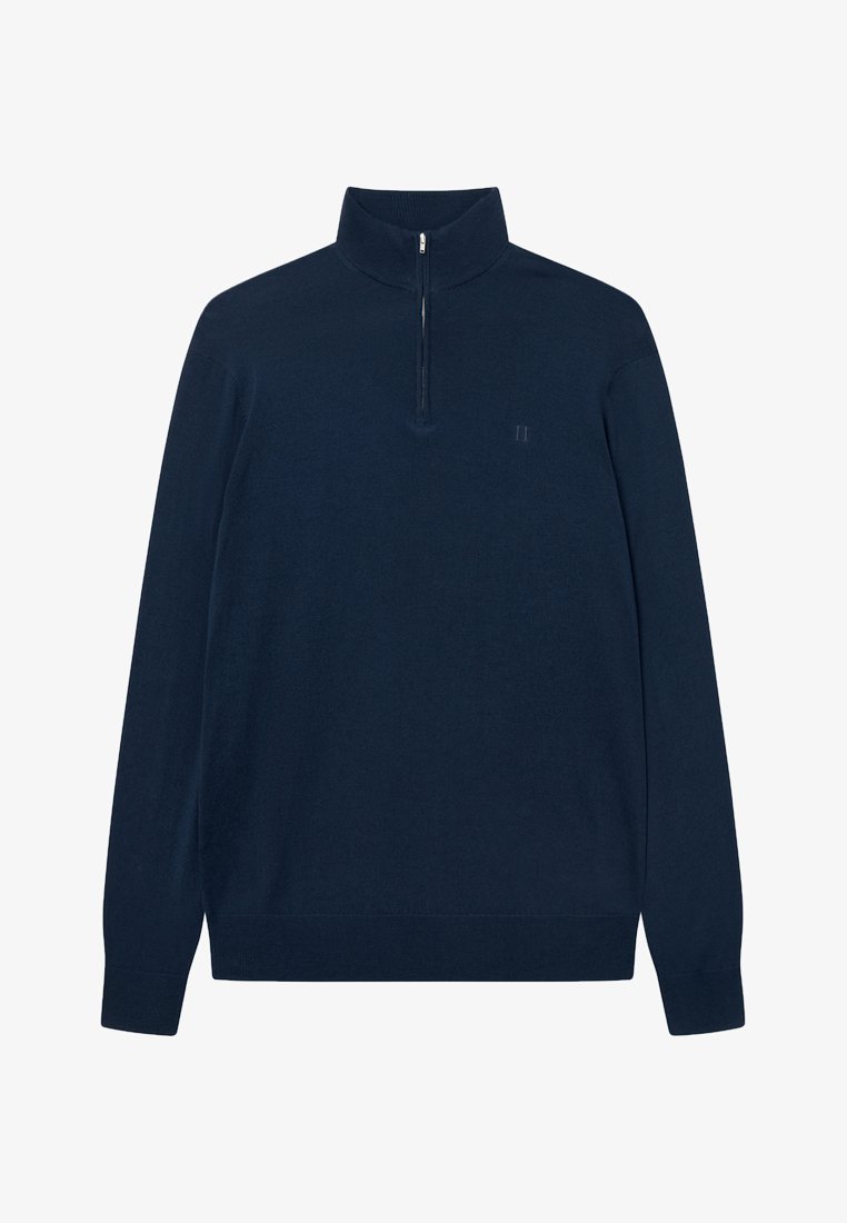 Mornarko modra, pulover z dolgimi rokavi in polovičnim zadrgo na ovratniku. Narejen iz mehkega materiala, z diskretnim logotipom na levem prsnem delu. Gladka tekstura.