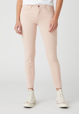 Vaaleanpunaiset kapeat farkut, joissa on sileä, hieman joustava kangas, viiden taskun malli ja yksittäinen napitus vyötäröllä.