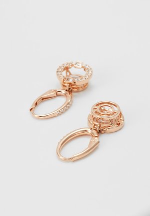 Rose gold naušnice s kružnim dizajnom, ukrašene prozirnim kristalima. Imaju zaklopnu kopču i složene detalje na metalnom radu.