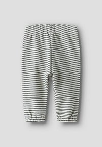 Pantalon bébé blanc à fines rayures horizontales noires, avec ceinture et poignets aux chevilles élastiques.