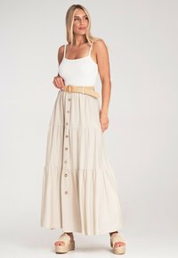 Beige Maxirock mit Stufen, Knöpfen, verstellbaren Trägern und einem geflochtenen Gürtel. Er hat eine weiche Textur und ein fließendes Design.