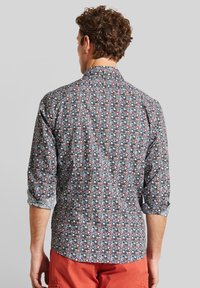 Hemd mit Knopfleiste, das ein mehrfarbiges Blumenmuster auf dunklem Hintergrund zeigt. Es hat lange Ärmel und einen klassischen Kragen. Aus Baumwollgewebe.