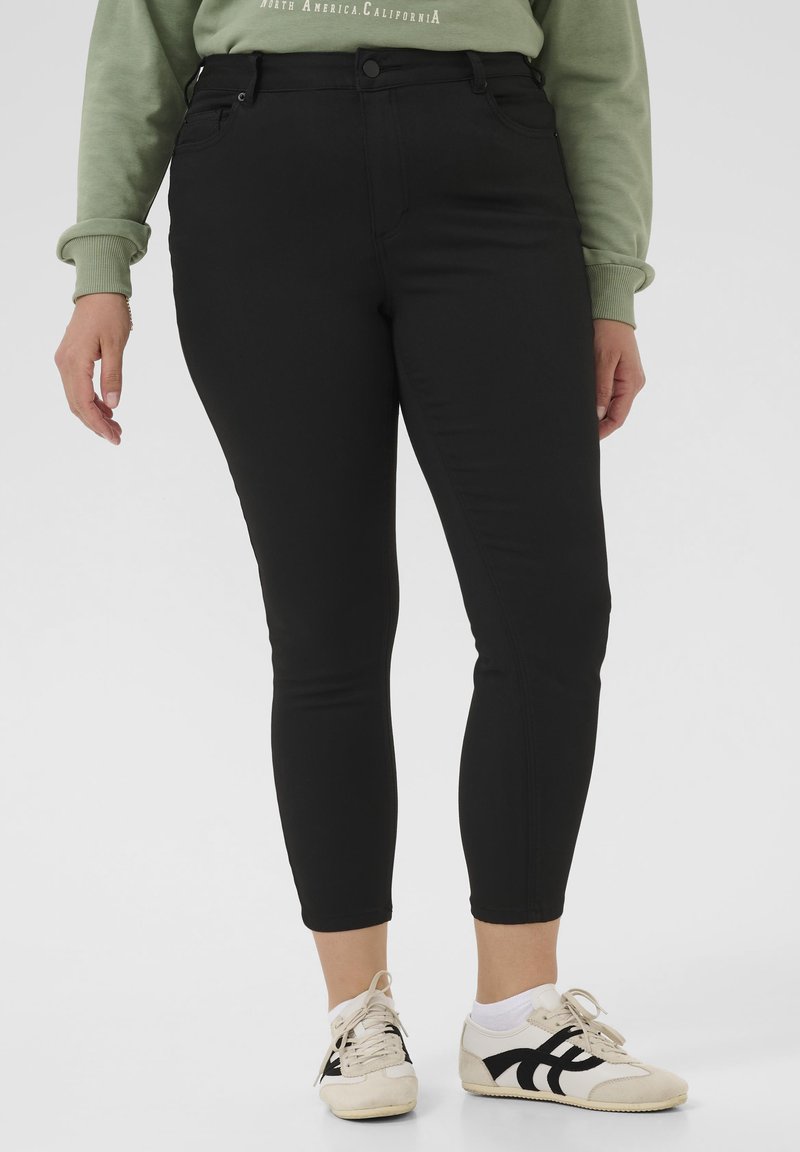 Sorte skinny jeans lavet af elastisk materiale med høj talje, glat tekstur og klassisk design med fem lommer. Bruges med lyse sneakers.