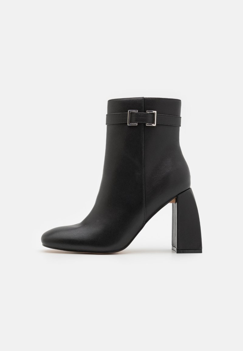Black leather ankle boot with block heel and decorative silver buckle strap around the upper front.