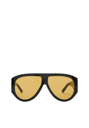 Lunettes de soleil avec une monture en plastique noir élégant et des verres teintés jaunes, dotées d'une forme angulaire distincte et de branches larges pour une meilleure protection.